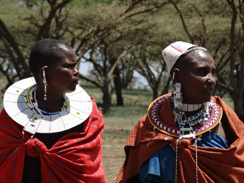 Two traditional Maasai women wearing the cultural saucer-like necklaces and bead earings, looking to their right