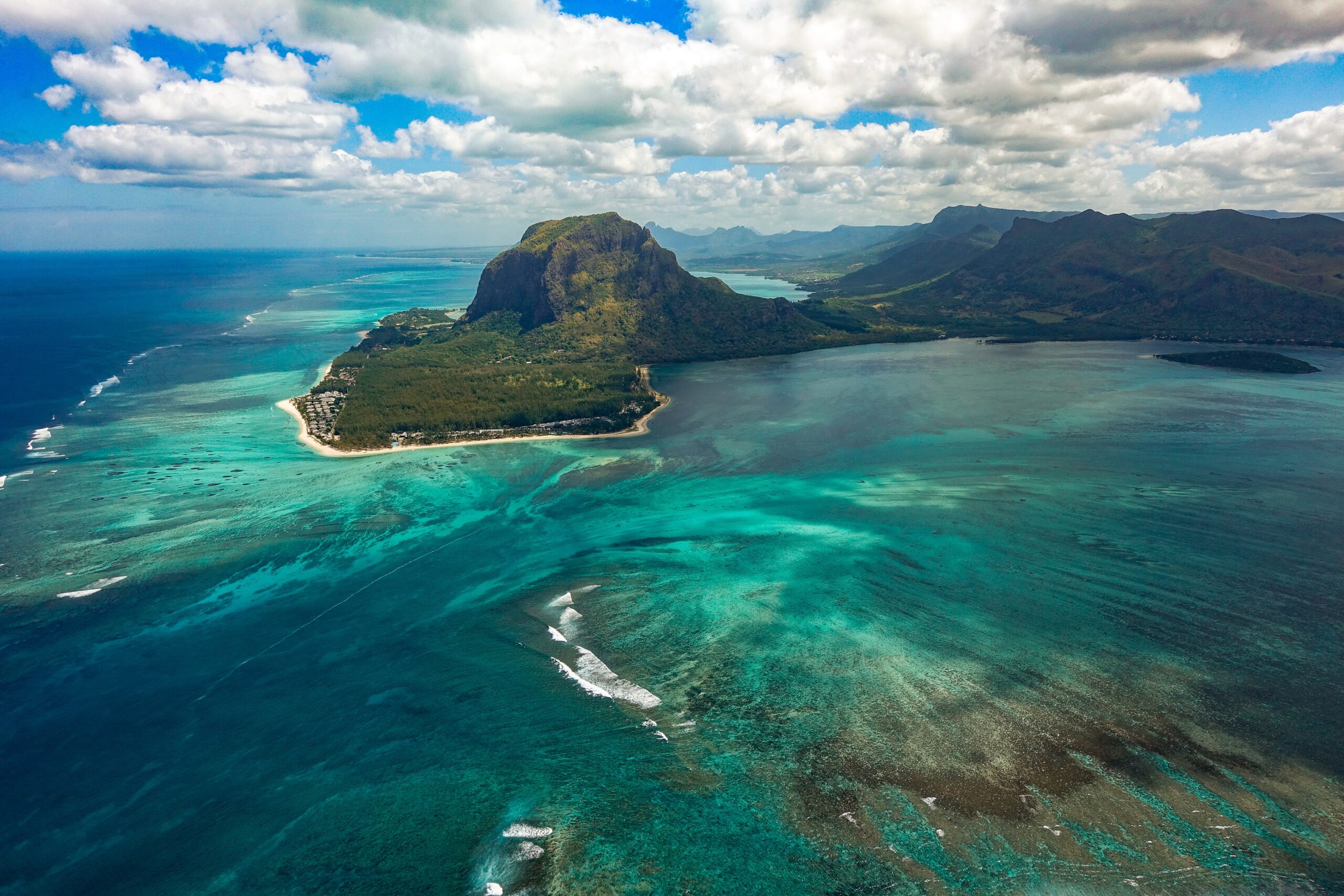 South of Mauritius, Le Morne, showing green and grey mountain peak in front of blue and green lagoon with underwater waterfall illusion