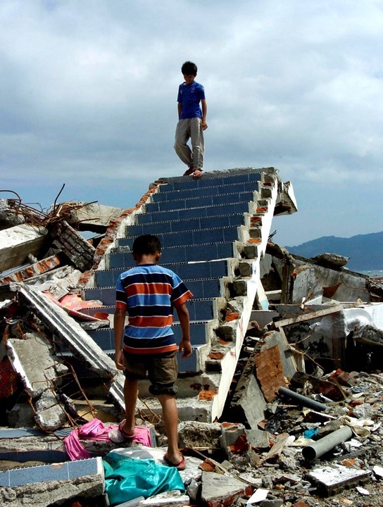 Positive and effects of tsunamis; one boy standing on stair ripped off of house and another boy standing in front of broken stair; tsunami effects in Thailand