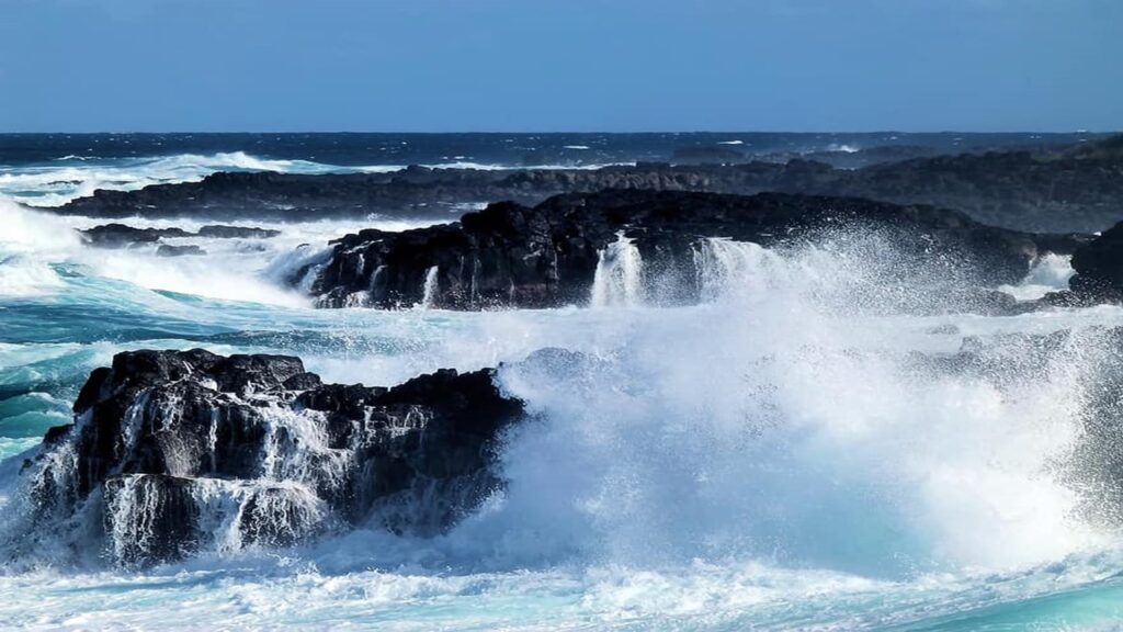 White foam of blue sea on black jutted rocks Waves crashing on rocks in the south of Mauritius as there are no coral reefs