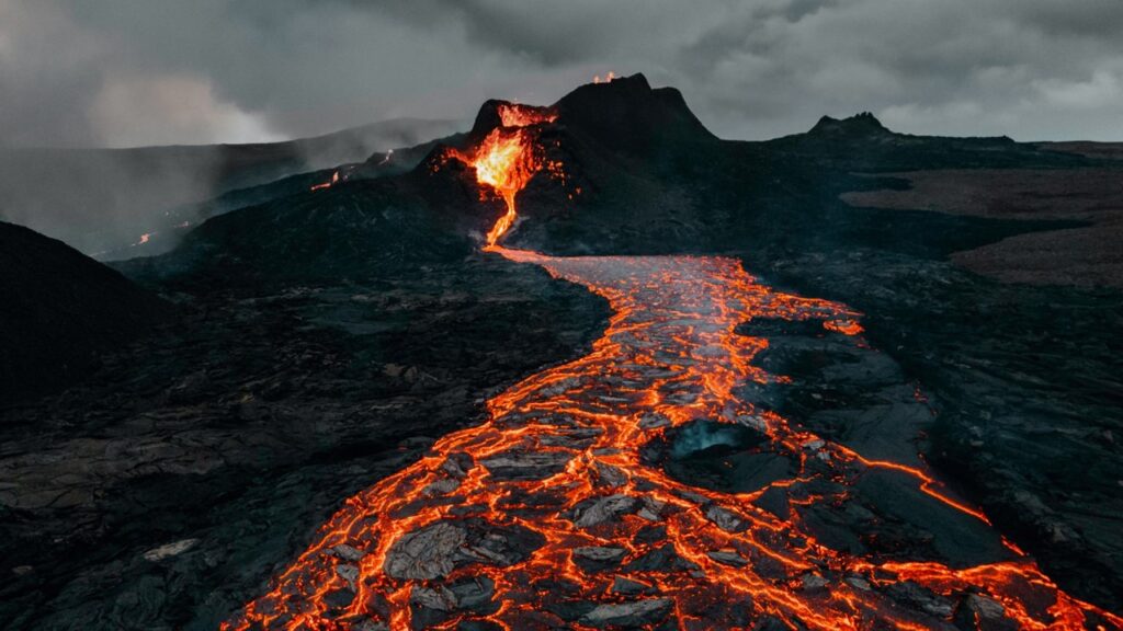Glowing lava on black terrain; volcanic eruptions explained, types, examples