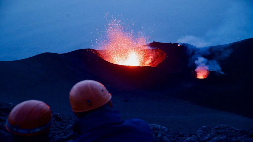 Glowing red lava erupting in dark volcanic crater of stromboli